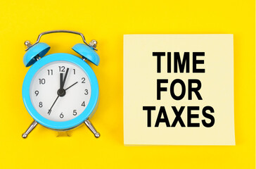 On a yellow background lie a clock and a sticker sheet with the inscription - TIME FOR TAXES