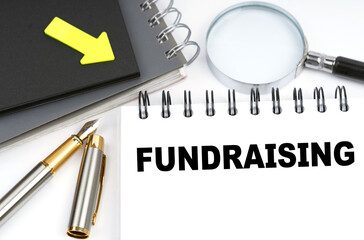 On the table are a pen and a notebook with the inscriptions - fundraising