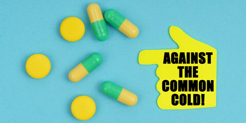 On a blue background, there are pills and a hand-sticker with the inscription - Against the common cold