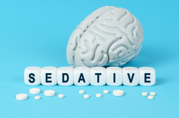 Cubes lie on the table among the pills and imitation of the brain. The text on the dice - SEDATIVE