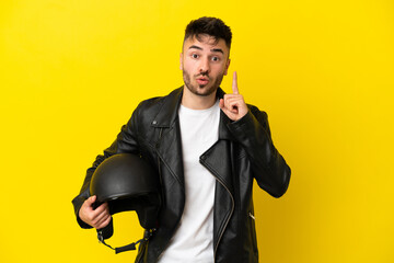 Naklejka premium Young caucasian man with a motorcycle helmet isolated on yellow background intending to realizes the solution while lifting a finger up