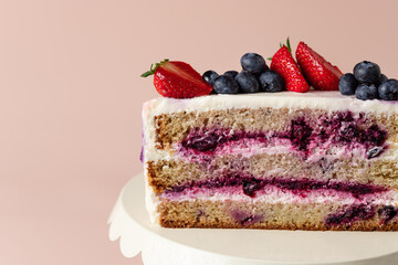 close up of half layered cake with blueberries and cream. sweet holiday treat. pink background. copy space