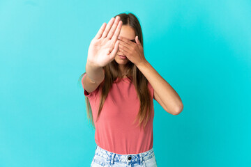 Young woman over isolated blue background making stop gesture and covering face