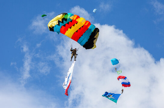 Parachute jumpers with flags on a blue sky background