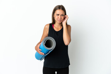 Sport woman going to yoga classes while holding a mat over isolated white background frustrated and covering ears