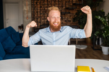 Excited redhead bearded male entrepreneur showing triumph gesture and screaming yes, young bearded man in shirt sits at the desk and using laptop indoor, celebrating good offer, finished project
