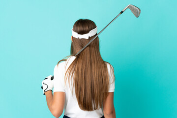 Young woman over isolated blue background playing golf and in back position
