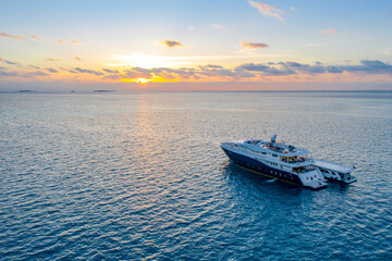 Naklejka premium Aerial view of sunset and tourist ship in the Indian ocean with a small island on the horizon