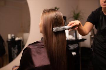 Naklejka premium coloring hair, Hair dyeing. Young professional hairdresser applies hair dye to a female client.