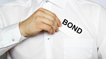 A businessman in a white shirt shows a business card with text BOND , copy space, business concept