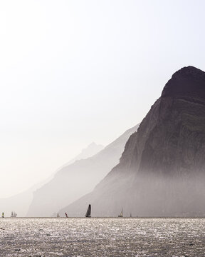 View of the Lago di Garda with fog, high mountains, surfs and boats