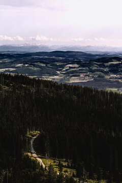 View from the Tristolicnik (Dreisesselberg) to the valley with forest, road, landscape with the Alps on the horizon and clouds in the sky