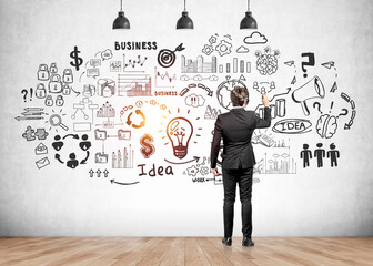 Businessman pen in hand drawing business strategy sketch on concrete wall