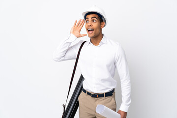 African American architect man with helmet and holding blueprints over isolated white background _ listening to something by putting hand on the ear