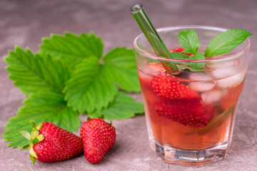 Strawberry drink with mint and ice in a glass on a gray background.
Close-up.