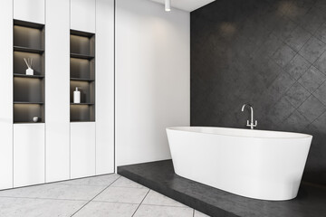 White bathtub in bathroom interior with mockup on black tiled wall