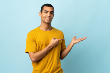 African American man over isolated background holding copyspace imaginary on the palm to insert an...