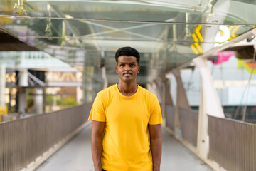 Portrait of handsome black African man wearing yellow t-shirt outdoors in city