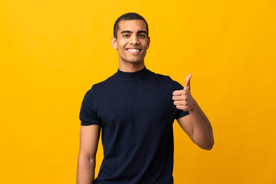 African American man counting numbres over isolated yellow background