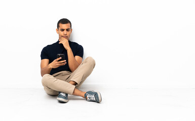 African American man sitting on the floor thinking and sending a message