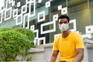 Fototapeta premium African man wearing yellow t-shirt and face mask outdoors in city