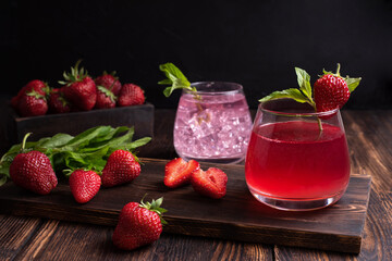 Fruit water, strawberry lemonade with mint sprig with strawberries on a wooden background, summer refreshing drinks concept.
