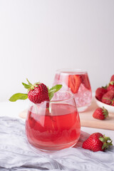Glasses with refreshing strawberry lemonade and strawberries on white background, summer fruit drinks concept.
