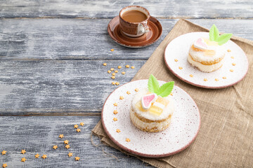 Decorated cake with milk and coconut cream with cup of coffee on a gray wooden background. Side view, copy space.