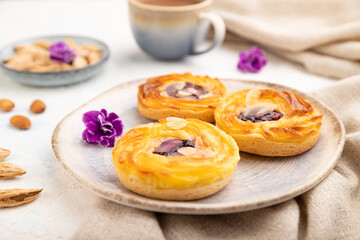 Small cheesecakes with jam and almonds with cup of coffee on a white concrete background. Side view, selective focus.