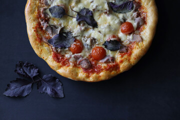 Delicious fresh pizza on a wooden table with basil leaves, mozzarella and cherry