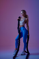 Young sportswoman with ropes poses in studio