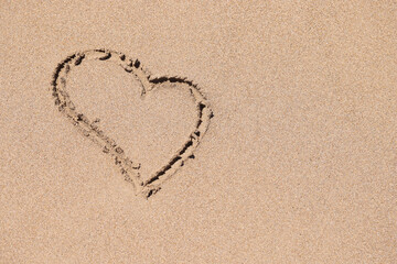 Drawn heart sign on wet sand on coastline