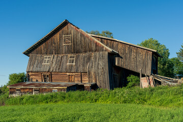 Fototapeta premium Abandoned farm with collapsing barn in summer.