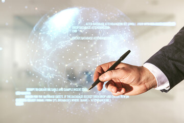 Male hand with pen working with abstract virtual coding illustration and world map on blurred office background, international software development concept. Multiexposure