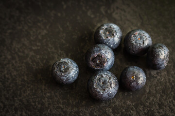 Wet blueberries on black cutting board. Forest berries with water drops on the table. Blueberries isolated. Summer harvest. Vitamin and antioxidant concept. Juicy dessert. Fresh ripe berries. 