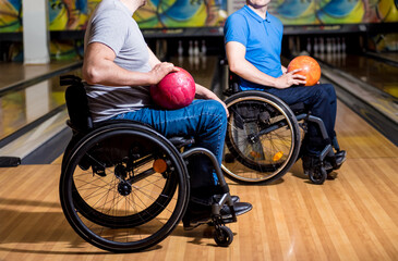 Two young disabled men in wheelchairs playing bowling in the club