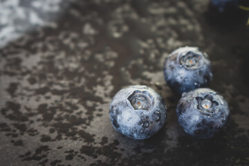 Wet blueberries on black cutting board. Forest berries with water drops on the table. Blueberries isolated. Summer harvest. Vitamin and antioxidant concept. Juicy dessert. Fresh ripe berries. 