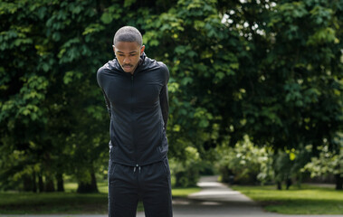 Portrait of black male athlete stretching in a park.