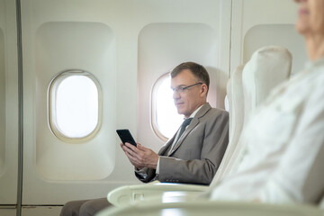 Professional businessman using smartphone while sitting in airplane,Business trip.