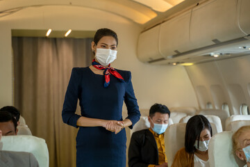 Air hostess wearing protective mask to Protect Against Covid-19 take care and check the orderliness of the plane passengers before departure,Air travel during the coronavirus pandemic.