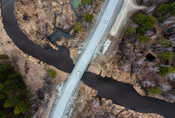 intersection of the road and river, the car passes over the bridge. Nature, view from drone.