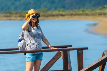 A young woman with spyglasses looking at the birds from the wooden piers of the Urdaibai marshes, a biosphere reserve in Bizkaia next to Mundaka. Basque Country
