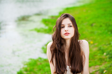 Portrait of a young beautiful brunette girl posing in summer park