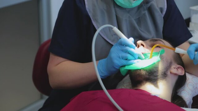 The dentist examines the patient's teeth with a special dental mirror. The guy at the dentist's appointment. dental treatment