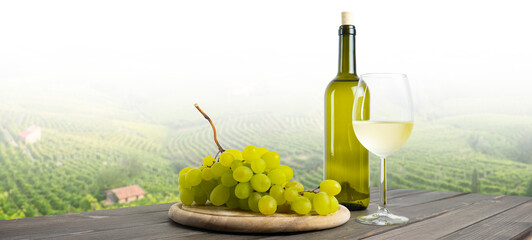 Italian white wine, bottle and glass of white wine with grapes on the wooden table, in the...