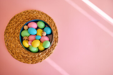 Colorful easter eggs in bowl, pink background