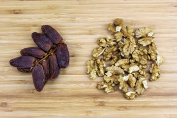 A sprig of date fruit with a walnut kernel on a wooden tray. Fruit dates fruits. A bunch of walnut kernels.