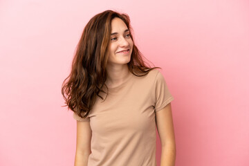 Young caucasian woman isolated on pink background looking to the side and smiling