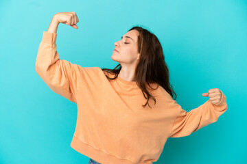 Young caucasian woman isolated on blue background doing strong gesture