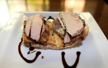 tostada de solomillo de cerdo con foie y sirope en plato blanco